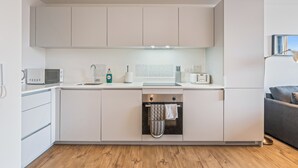 A modern kitchen with white cabinetry, a microwave, a toaster, and an oven. - Apt-sleeps 2/3-bullring & Grand Central Close (Birmingham)