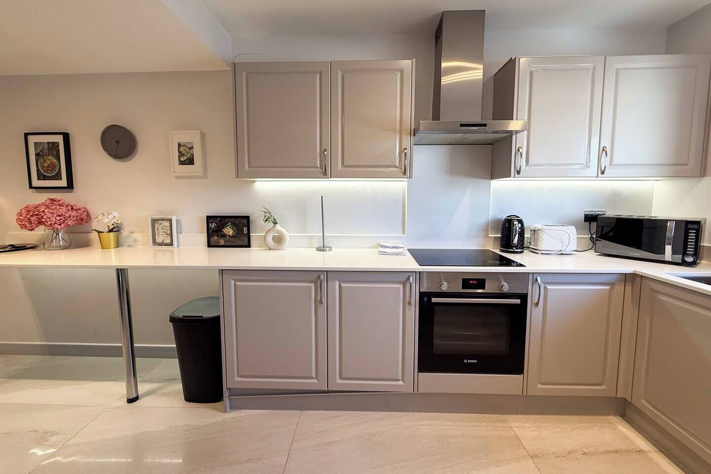 A modern kitchen with a built-in oven, microwave, and stainless steel range hood.