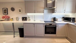 A modern kitchen with a built-in oven, microwave, and stainless steel range hood. - Contemporary 2 Bed Apt in Didcot (Sleeps 7) (Didcot)
