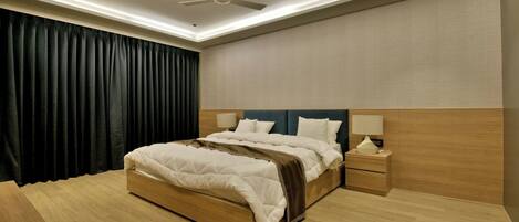 A modern hotel bedroom with a large bed, wooden headboard, bedside lamps, and a ceiling fan.