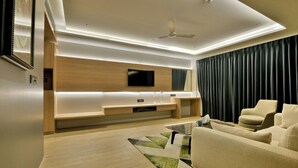 A modern living room with a flat-screen TV, a ceiling fan, and a sofa. - Kratos Club (Surat)