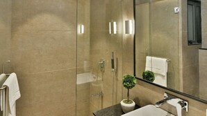 A modern bathroom with a glass-enclosed shower, a white sink, and a large mirror. - Kratos Club (Surat)