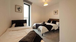 Een hotelkamer met twee bedden, een groot raam en een plafondlamp.