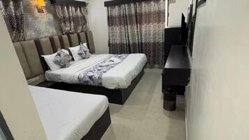 A modern hotel room with two beds, a flat-screen TV, and a small desk.