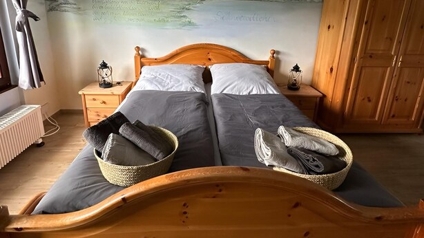 A bedroom with a wooden bed, a nightstand, a lamp, a radiator, and a wardrobe. - Enchanting apartment "Schneewittchen" - Live at the Silbersee Frielendorf. (Frielendorf)