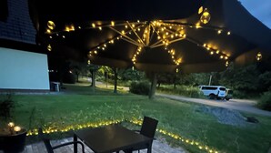 An outdoor patio with a table and chairs, surrounded by a brick floor and a grassy area. - Enchanting apartment "Schneewittchen" - Live at the Silbersee Frielendorf. (Frielendorf)