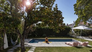 A backyard with a swimming pool, a hammock, and a patio area with cushions. - Casa dos Limões - Oeste (Bombarral)