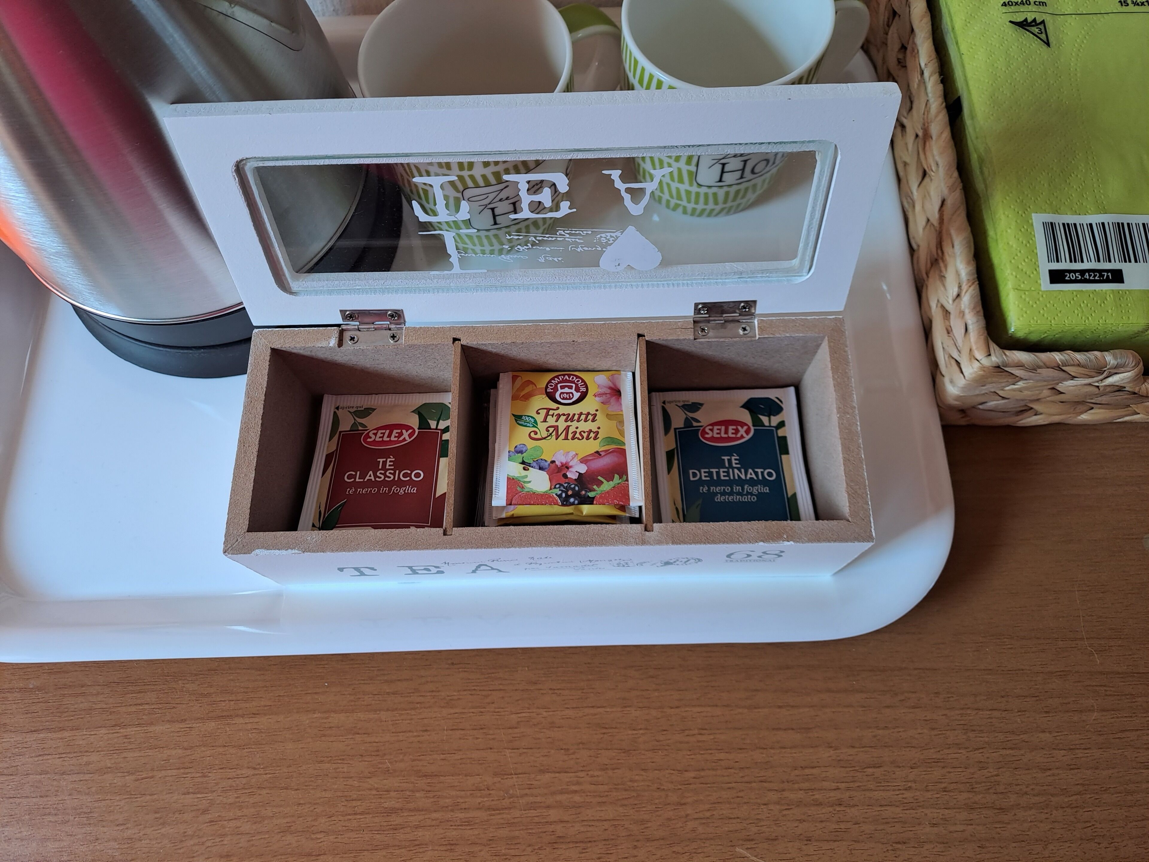 Une boîte en bois contenant trois boîtes à thé étiquetées « SELEX », le tout posé sur un plateau blanc.