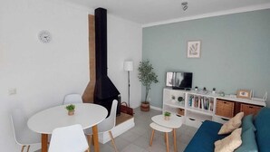 A modern living room with a dining area, a blue sofa, a TV, and a fireplace. - Apartment with terrace close to the sea (L'Escala)