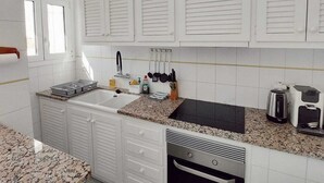 A modern kitchen with white cabinets, a granite countertop, a dishwasher, and a coffee maker. - Apartment with terrace close to the sea (L'Escala)