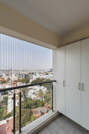 Un balcon avec vue sur la ville, une balustrade et des meubles blancs.