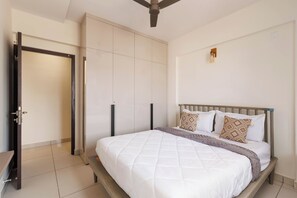 Une chambre à coucher avec un lit, une armoire et un ventilateur de plafond.