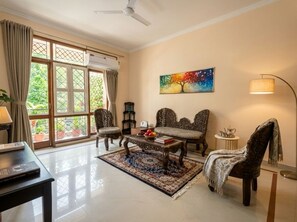 Un salon avec un canapé, des fauteuils, une table basse et un tableau accroché au mur.