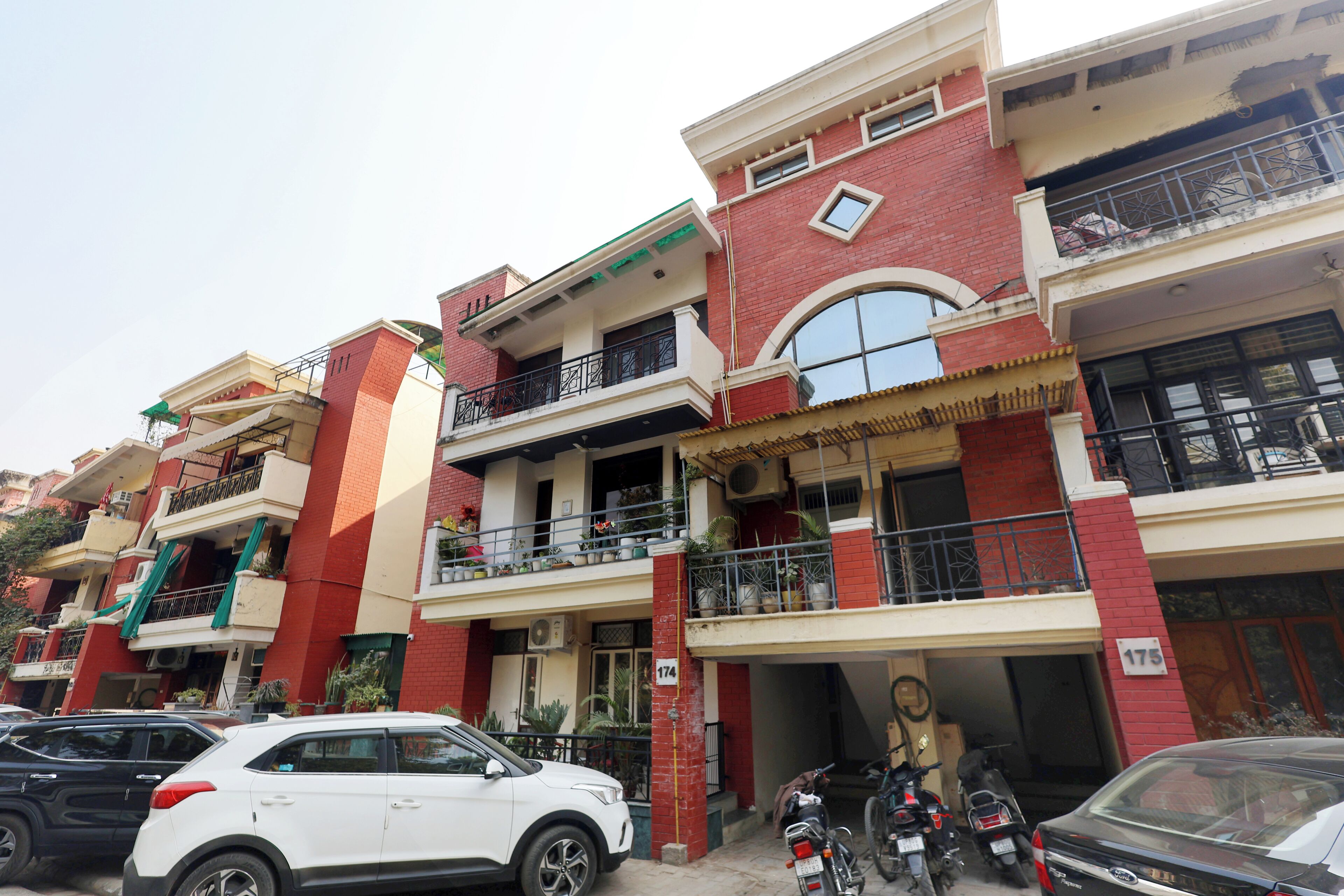 Un edificio residencial de varios pisos con balcones, un garaje y vehículos estacionados.