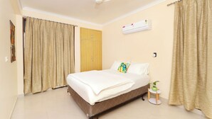 A bedroom with a bed, curtains, an air conditioning unit, and a small table with a plant. - Taj Luxuria by Red Olive10min to Taj Mahal3bhk (Agra)