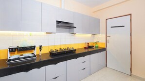A modern kitchen with white cabinets, a black countertop, and a stainless steel range hood. - Taj Luxuria by Red Olive10min to Taj Mahal3bhk (Agra)