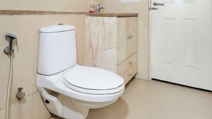 Une salle de bain avec des toilettes, un lavabo, un miroir et une porte.