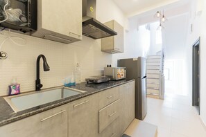 A modern kitchen with a black faucet, stainless steel appliances, and a large window. - Calcutta Heritage by Jadecaps Shyambazar 2BK (Kolkata)