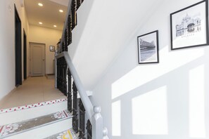 Un escalier agrémenté d’une rampe décorative et d’un tableau encadré représentant un pont, accroché au mur.