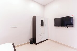 A bedroom with a wardrobe, a TV mounted on the wall, and a power outlet.