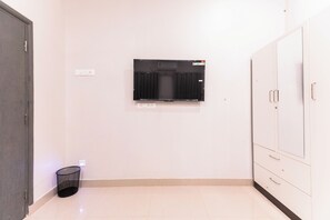 Une chambre dotée d’un téléviseur à écran plat fixé au mur, d’une poubelle et d’une armoire à plusieurs portes.