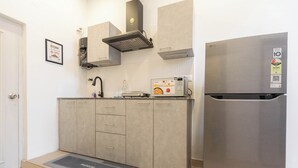 A modern kitchen with grey cabinets, a stainless steel refrigerator, and a built-in microwave. - Calcutta Heritage by Jadecaps Shyambazar 2BK (Kolkata)