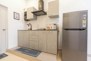 Une cuisine moderne avec des meubles gris, un réfrigérateur en acier inoxydable et un four à micro-ondes encastré.