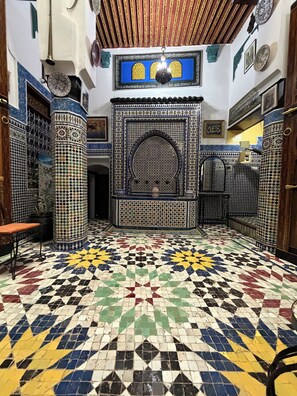 A room with a patterned tile floor, a central arched niche, and decorative wall tiles. - Riad Dar Fes source bleue luxury home  (Fes)