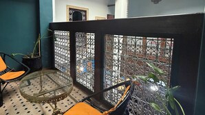 Ein Balkon mit zwei Korbstühlen, einem Glastisch und Topfpflanzen.