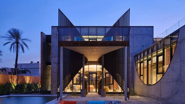 Ein modernes Gebäude mit einem zentralen Atrium, einer Außenbereich-Sitzgelegenheit und einem Pool.