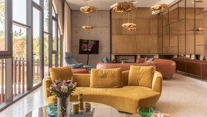 Ein modernes Wohnzimmer mit einem gelben Sofa, einem Glastisch und einem an der Wand befestigten Fernseher.