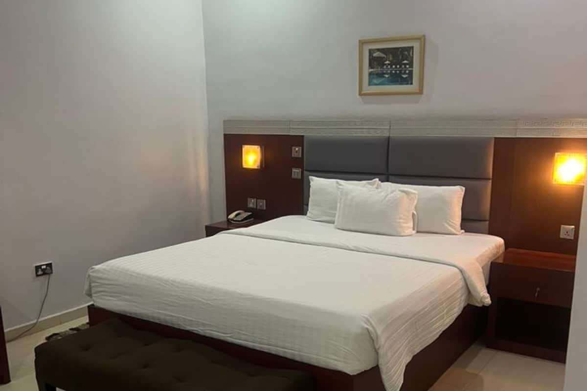 Une chambre à coucher bien rangée, avec un grand lit, des tables de chevet et un banc.
