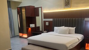 Een moderne hotelkamer met een groot bed, een bankje, een kledingkast en een spiegel.