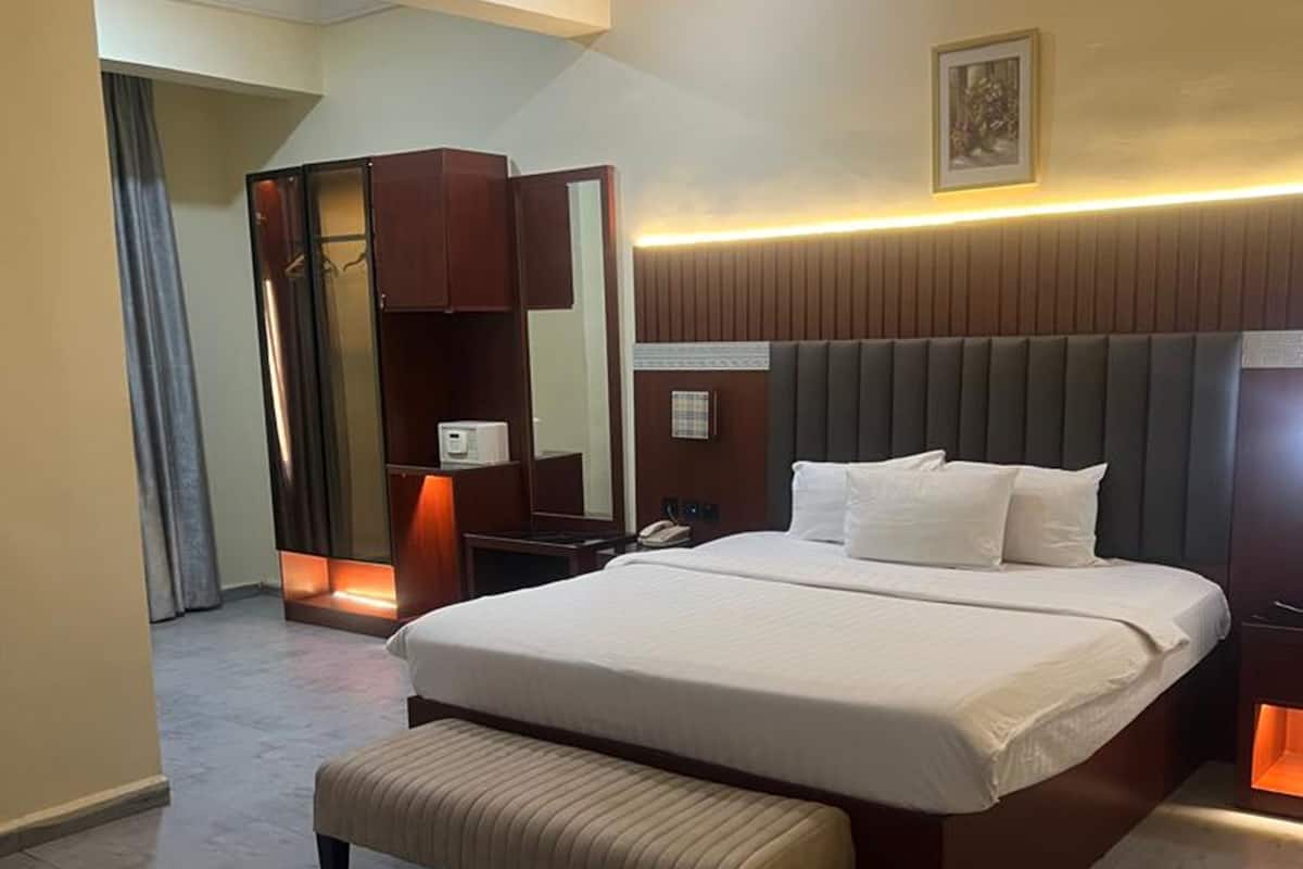 Une chambre d’hôtel moderne avec un grand lit, un banc, une armoire et un miroir.