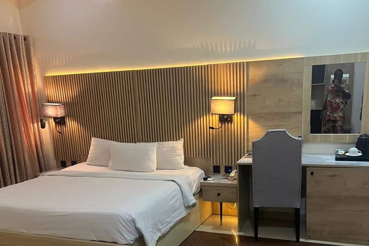 Une chambre d’hôtel avec un lit, des tables de chevet, un bureau et un miroir.