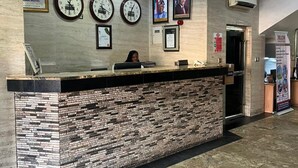 Een receptiebalie met een stenen aanrecht, klokken, ingelijste certificaten en een portret aan de muur.