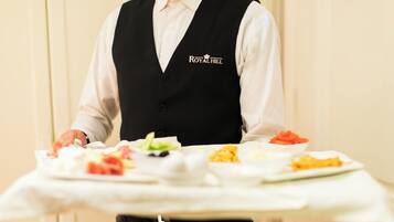 A person in a black vest with "ROYAL HILL" logo carrying a tray with various dishes.