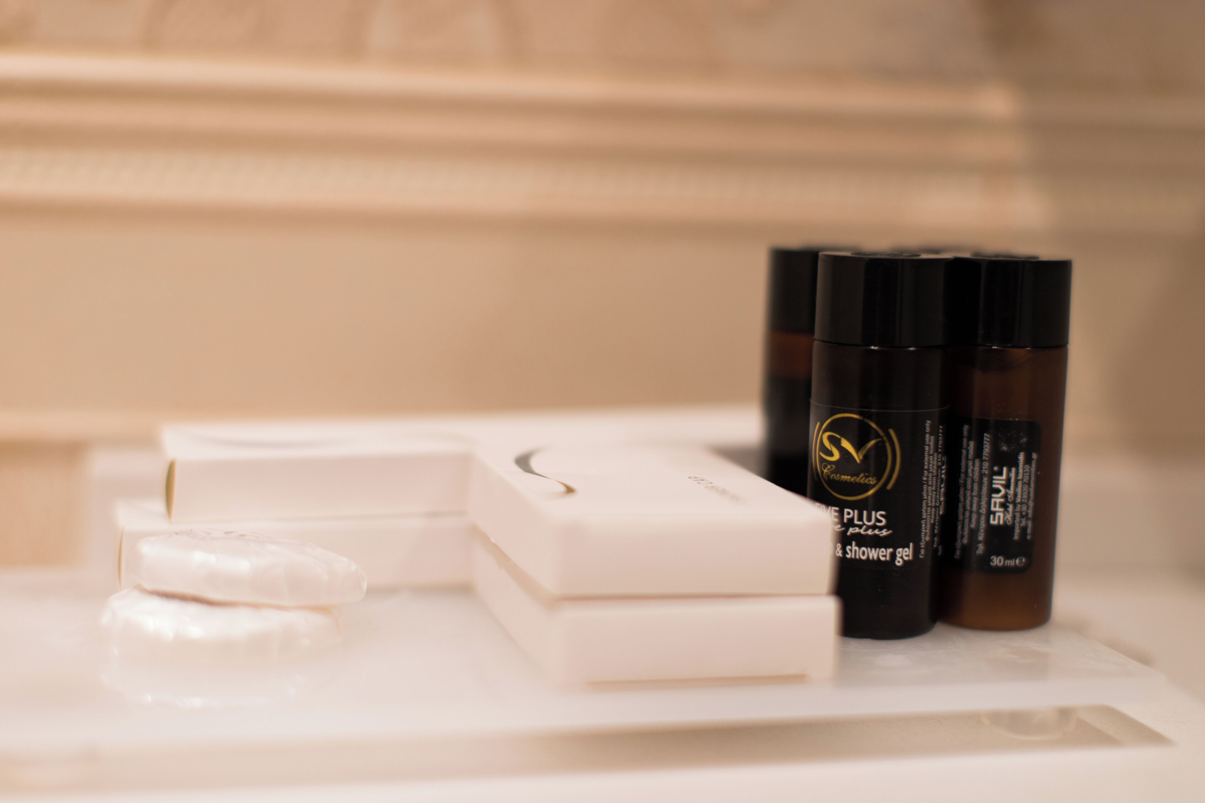 A bathroom vanity with a white countertop, a soap bar, and two bottles of shower gel.