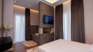 A modern hotel room with a large bed, a TV mounted on the wall, a built-in sink, and a view of the city through the window.