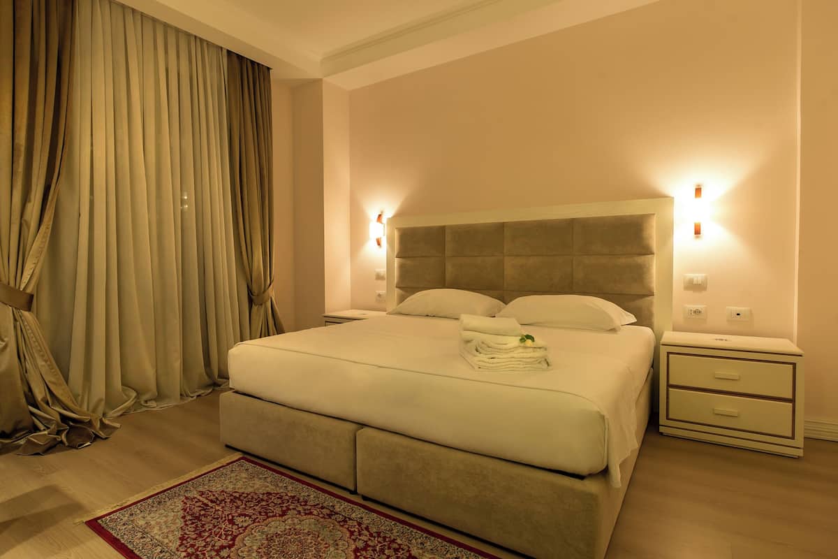 Une chambre d’hôtel équipée d’un lit, d’un bureau, d’une chaise, d’une table de chevet et d’une lampe fixée au mur.