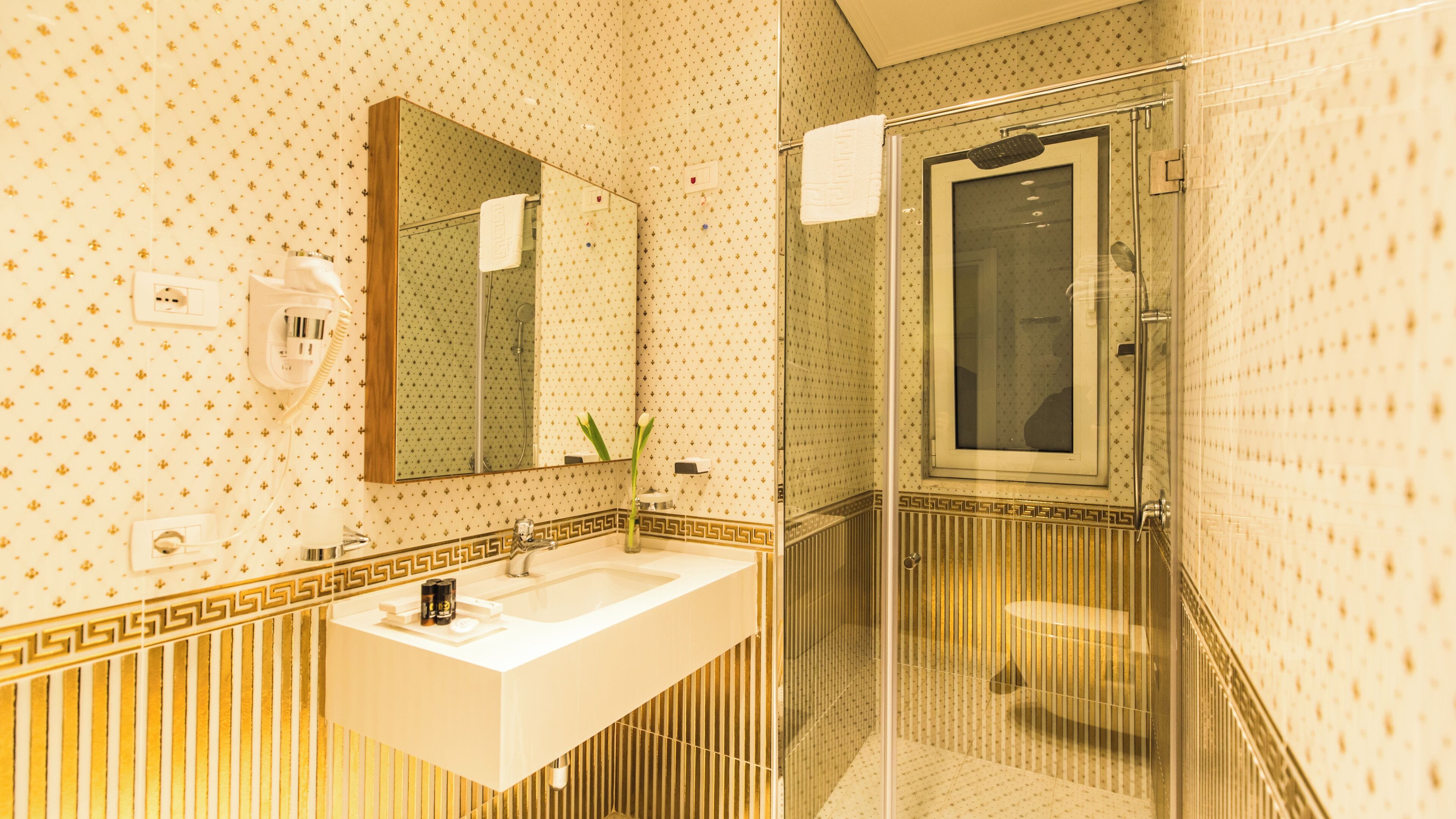 A bathroom with a sink, mirror, and shower area.