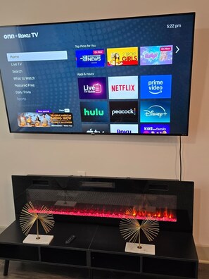 Ein Roku-Fernseher zeigt verschiedene Streaming-Dienste, darunter ein Kamin darunter.