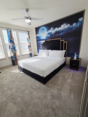 Ein Schlafzimmer mit einem Bett, einem Nachttisch, einem Deckenventilator und Wandgemälde.
