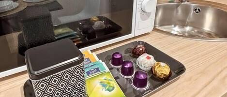 A kitchen with a microwave, a kettle, a sink, and a tray with food items and a box of Menthe.