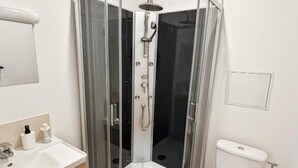 A modern bathroom with a glass-enclosed shower, a white toilet, and a wooden vanity with a sink. - Au42BisJM (Cambrai)