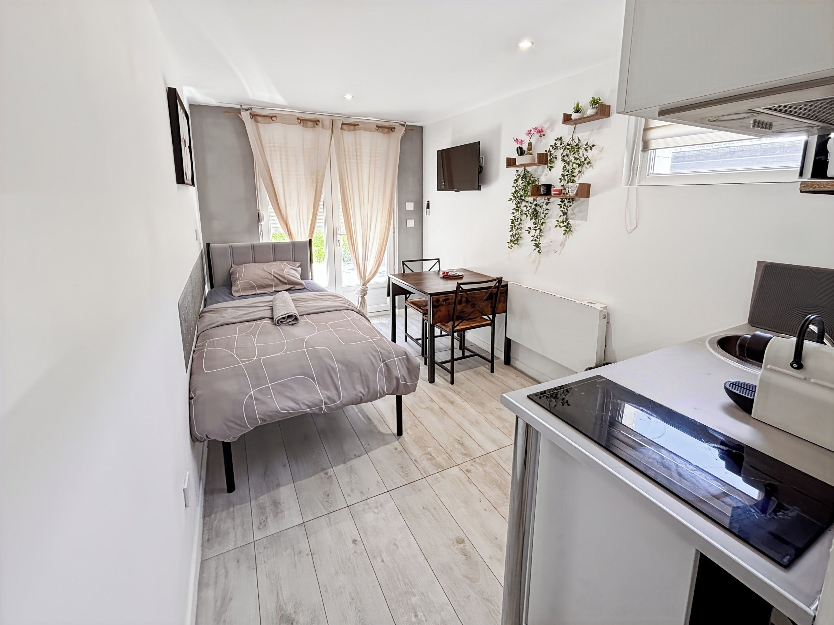 Ein kleines Schlafzimmer mit einem Bett, einem Schreibtisch und einer Küchenzeile.