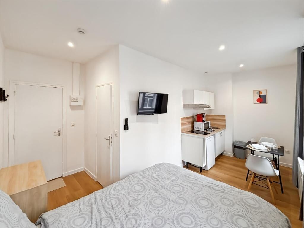 Een compacte hotelkamer met een bed, een kleine kitchenette, een televisie en een zithoek.