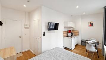 Een compacte hotelkamer met een bed, een kleine kitchenette, een televisie en een zithoek.