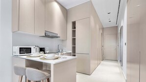 Una cocina moderna con una isla central, taburetes de bar, un microondas y copas de vino.