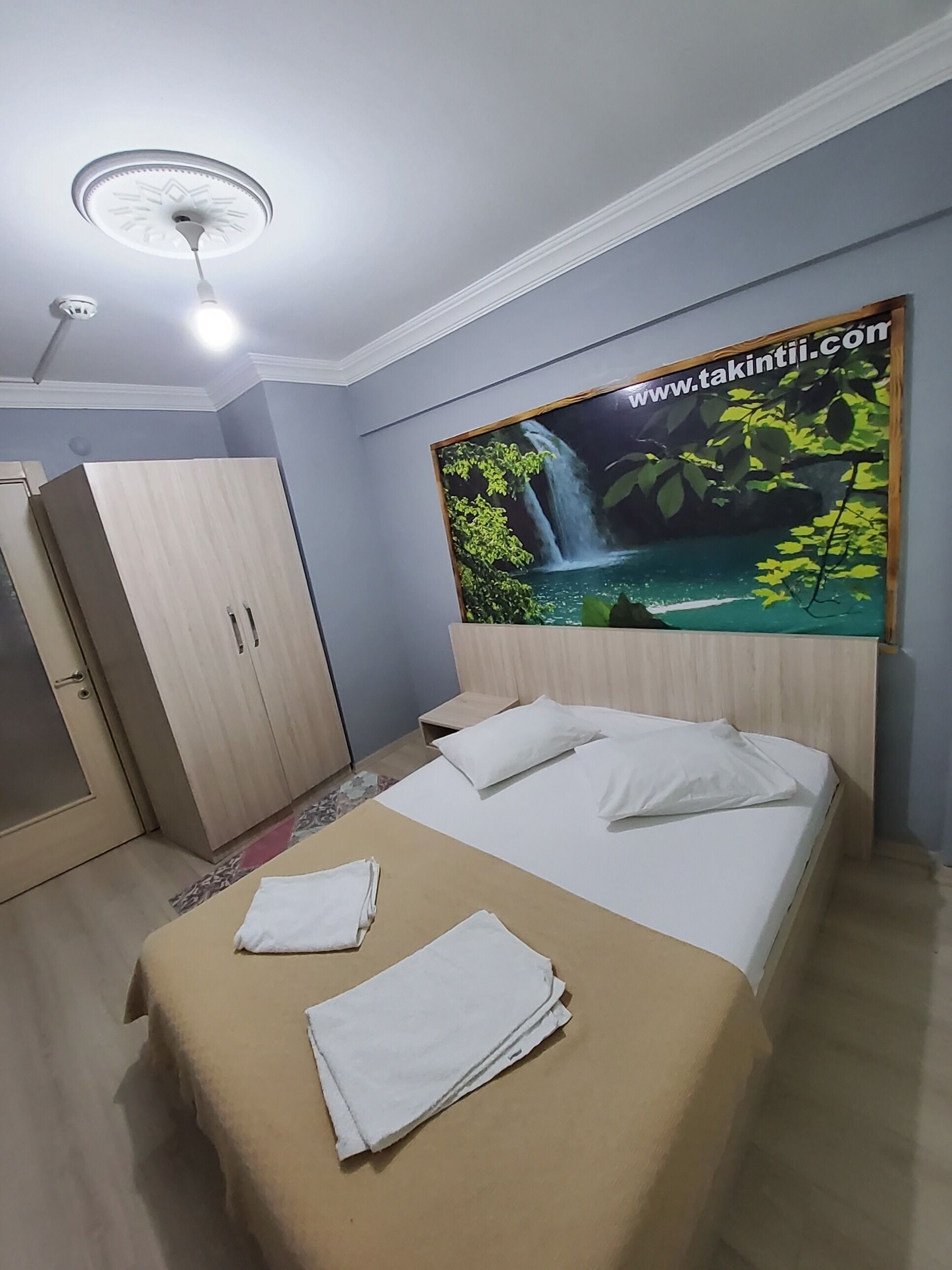 A hotel room with a bed, a wardrobe, and a wall-mounted artwork.